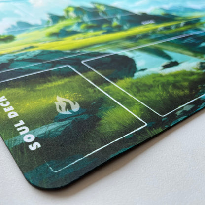 Palworld TCG playmat featuring the Emerald Highlands fantasy landscape with towering green mountains, a crystal-clear lake, and lush meadows. The 24x14-inch playmat includes clearly labeled game zones for Base, Soul Area, Soul Deck, Deck, Graveyard, Exile, Materials, Ingredients, Life, and Pal cards. Premium full-color artwork with an organized layout designed for casual and competitive Palworld TCG gameplay.